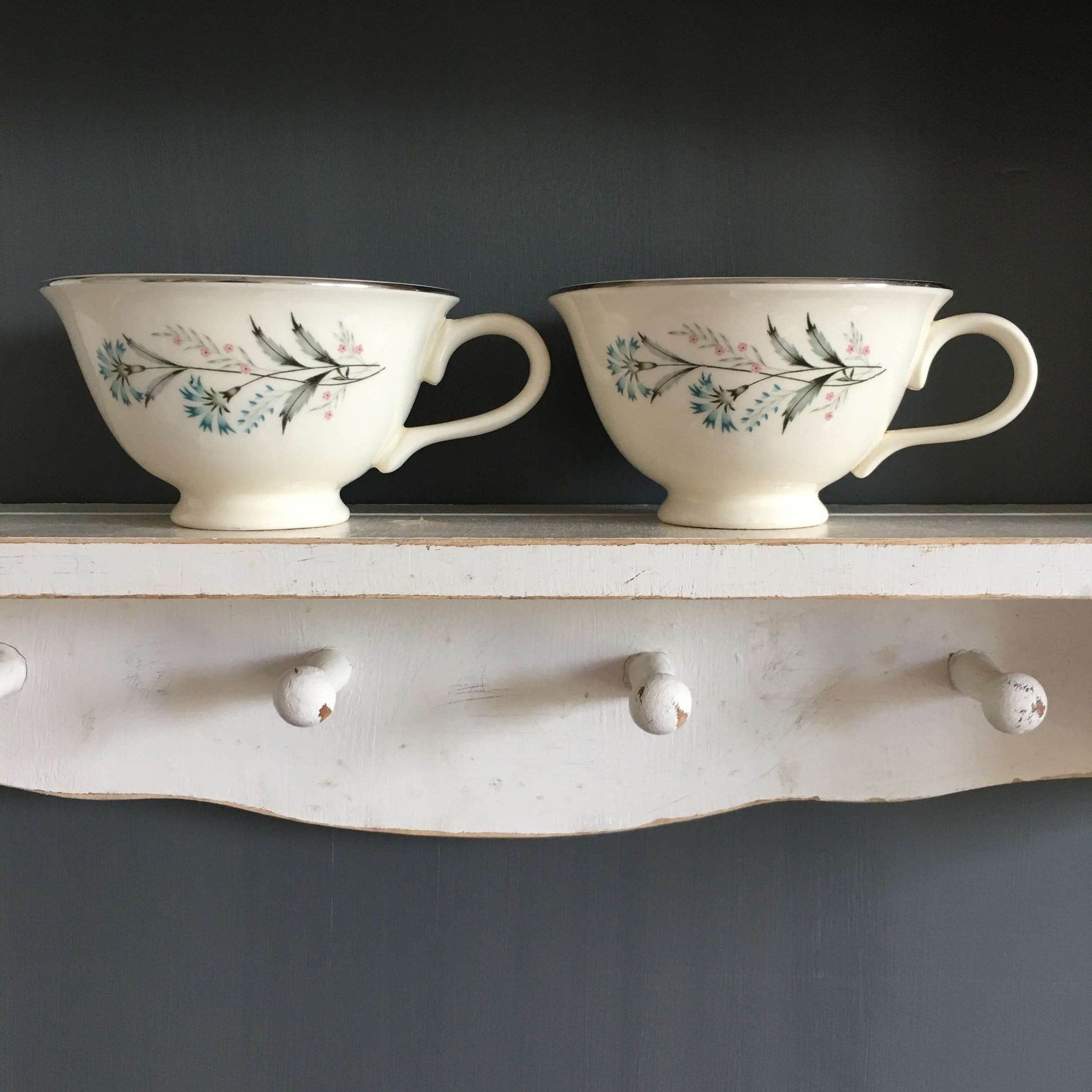 two vintage taylor smith taylor teacups bachelor button pattern on a shelf